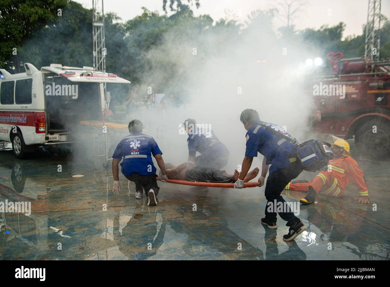 Unknown rescuers and fire brigade Conduct fire-rescue drills by pulling wagons with the injured. Put on a ventilator and take him to an ambulance. Stock Photo