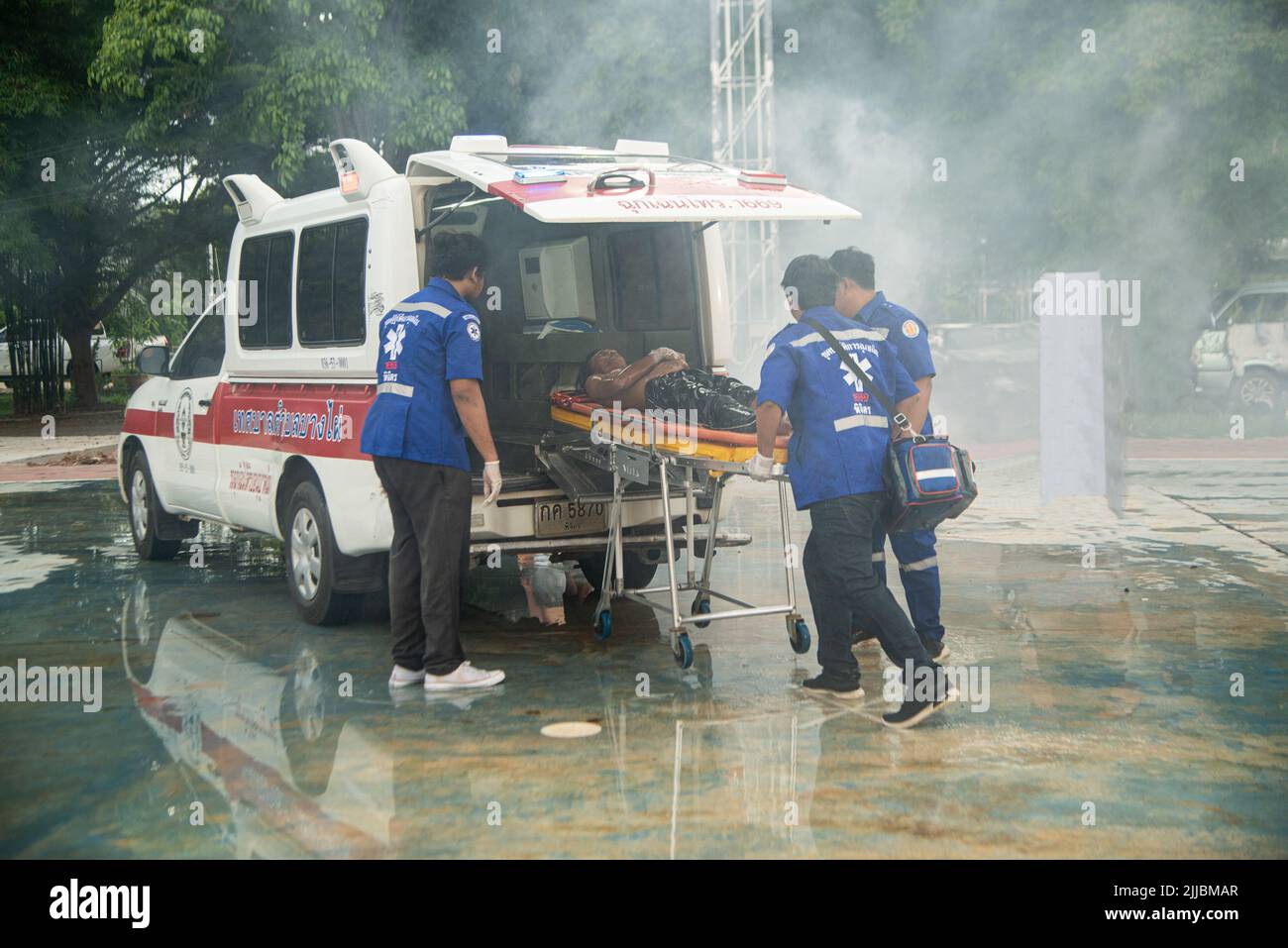 Unknown rescuers and fire brigade Conduct fire-rescue drills by pulling wagons with the injured. Put on a ventilator and take him to an ambulance. Stock Photo
