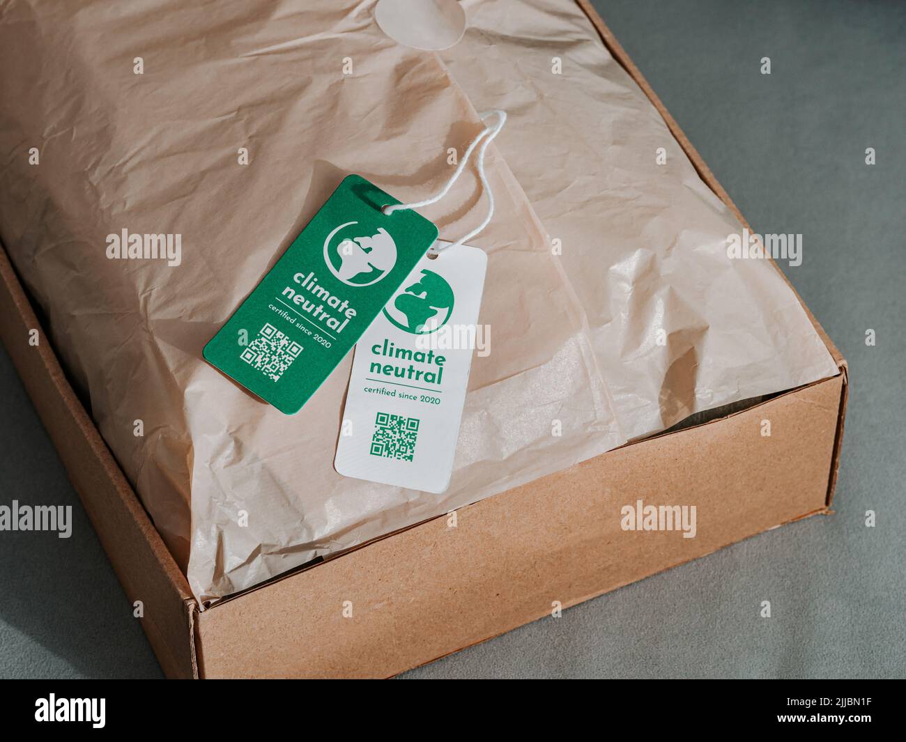 Carbon neutral product in craft corrugated box with label Climate neutral. Carbon neutral label concept in apparel, fashion, logistics indusrty and ethical consumption. Increasing awareness for customers about carbon footpint Stock Photo
