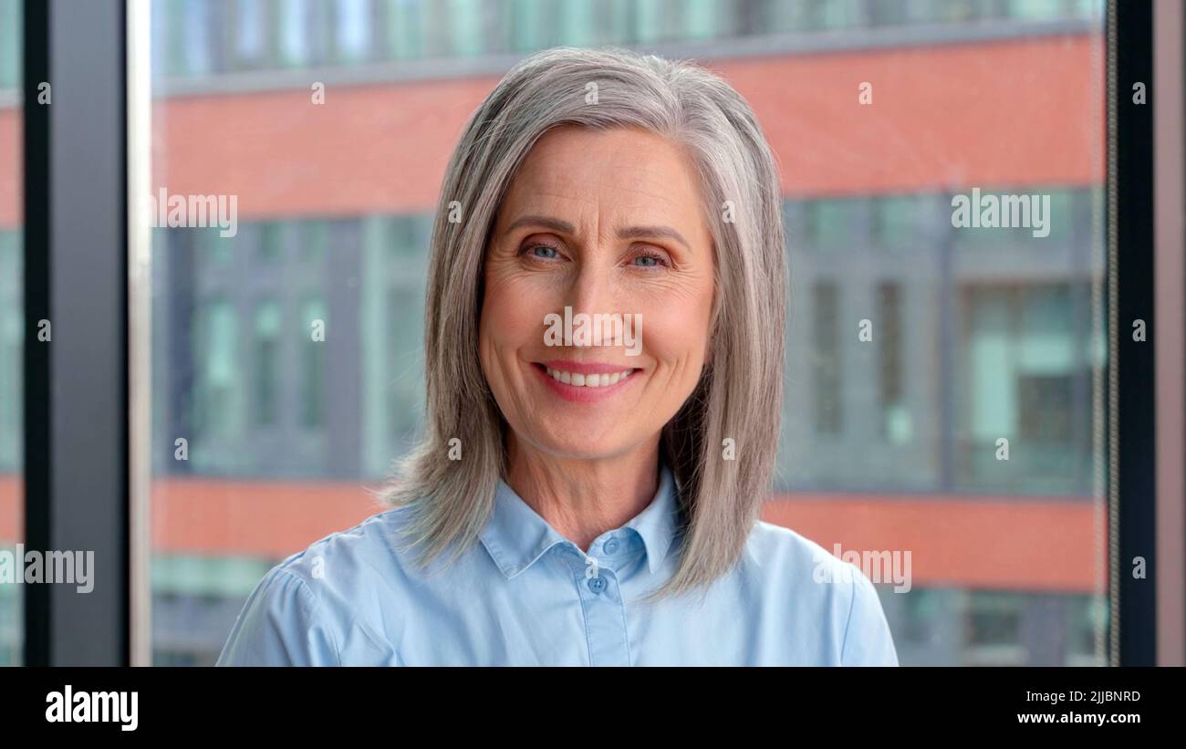 Portrait of smiling confident 60-s gray-haired mature woman. Stock Photo