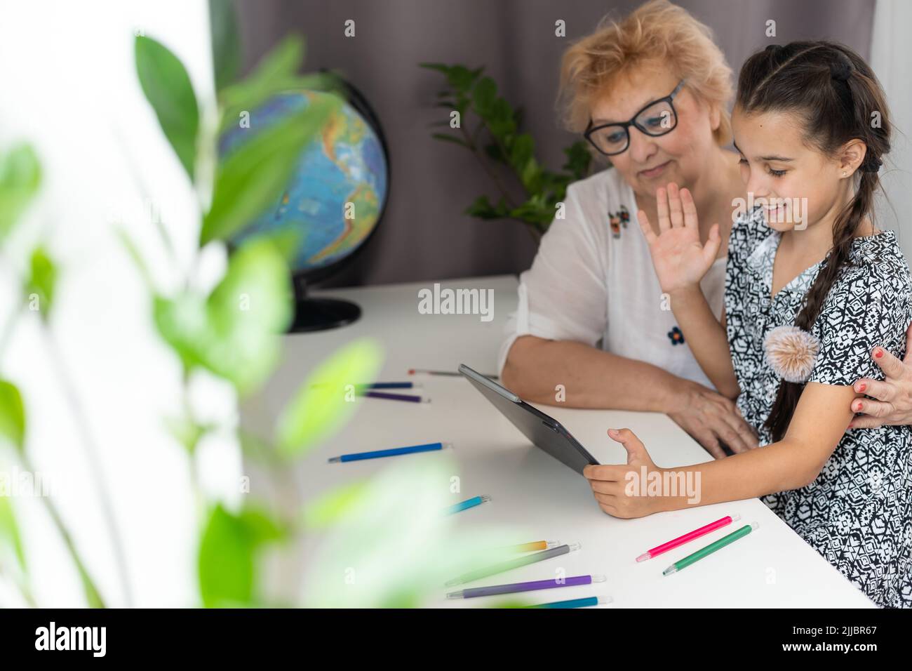 Cute little girl with her grandmother looking at tablet at home Stock ...