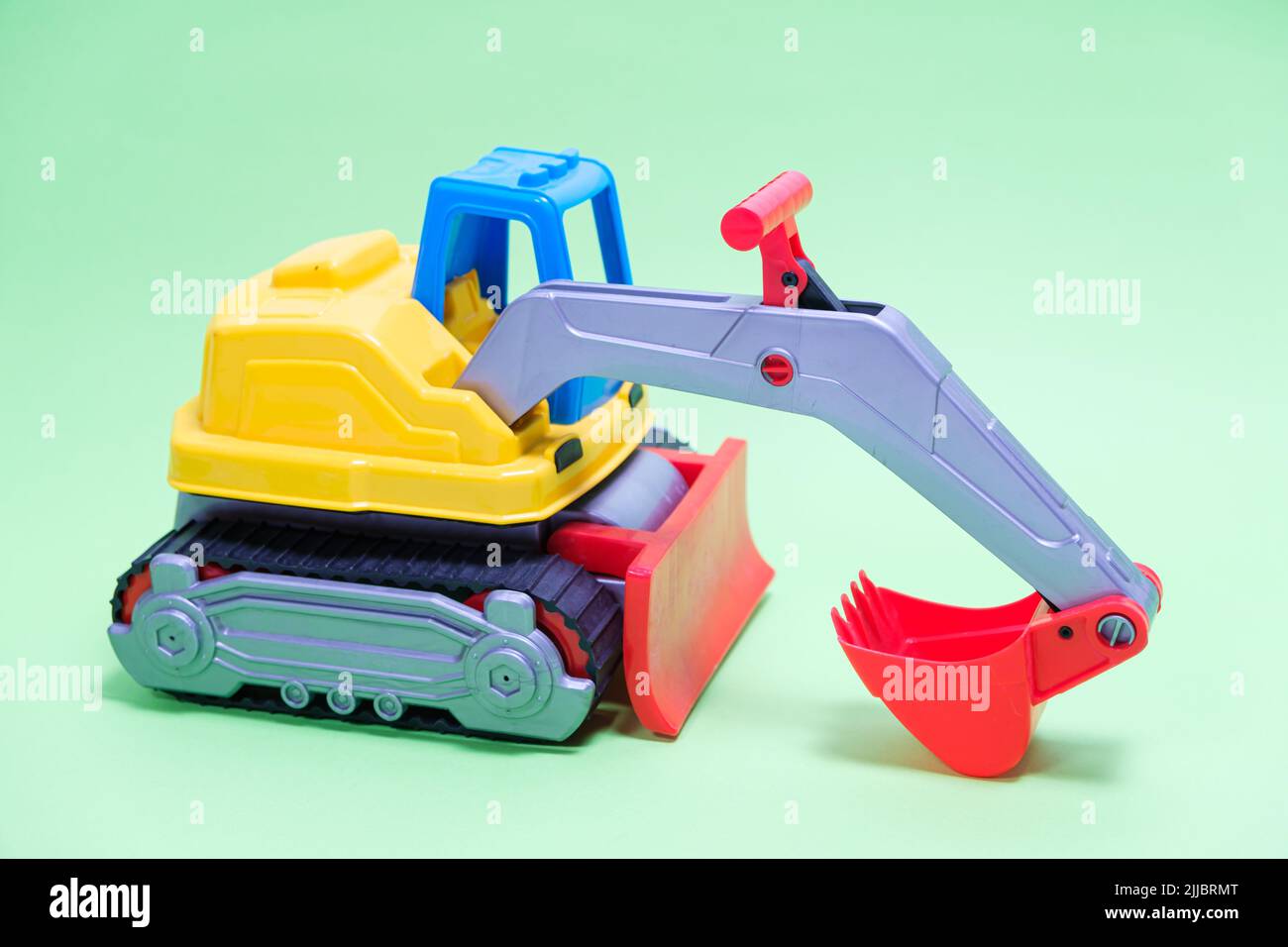 Yellow excavator plastic car on green background. Construction ...