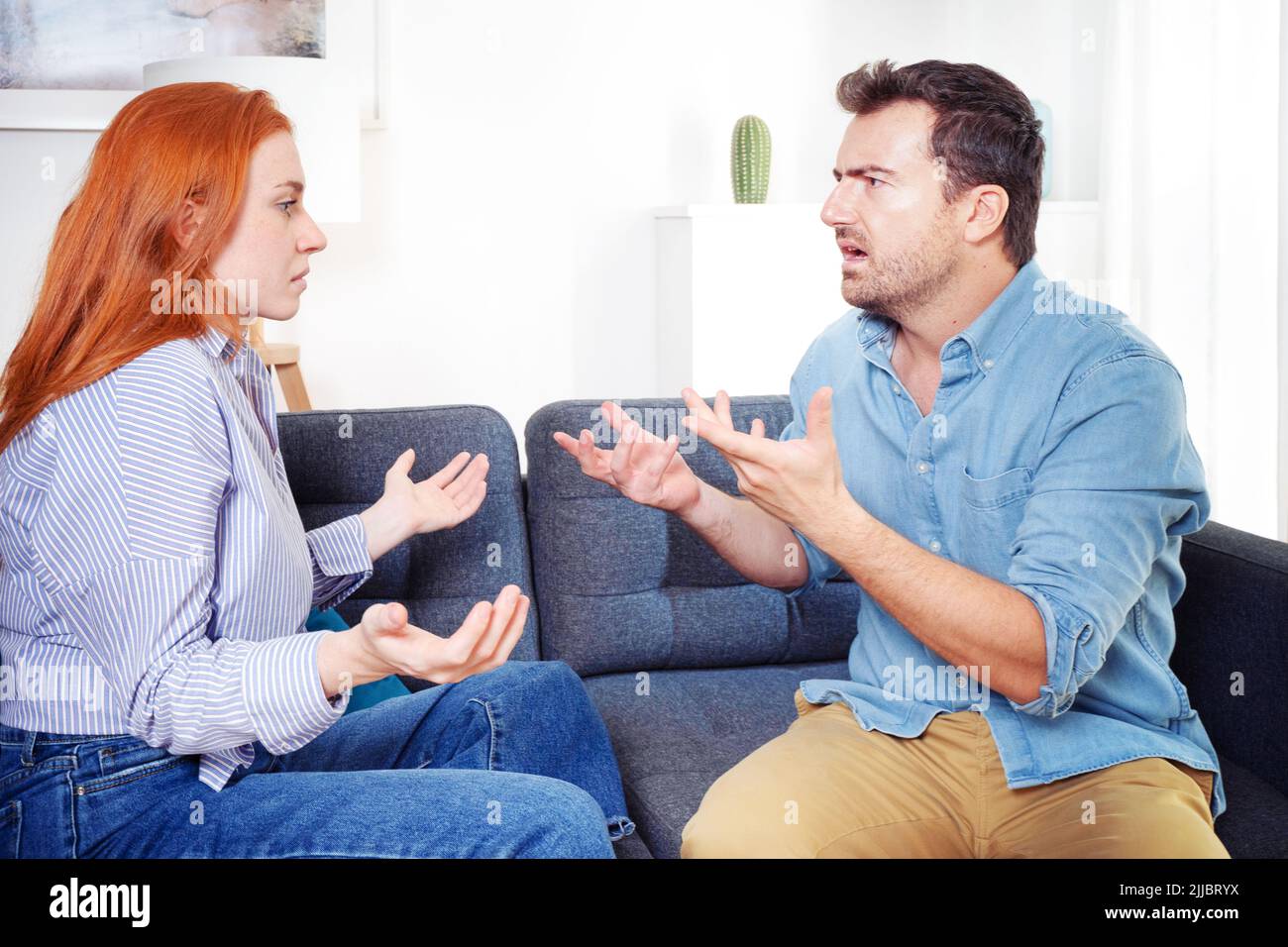 Upset and sad couple arguing with each other on sofa Stock Photo