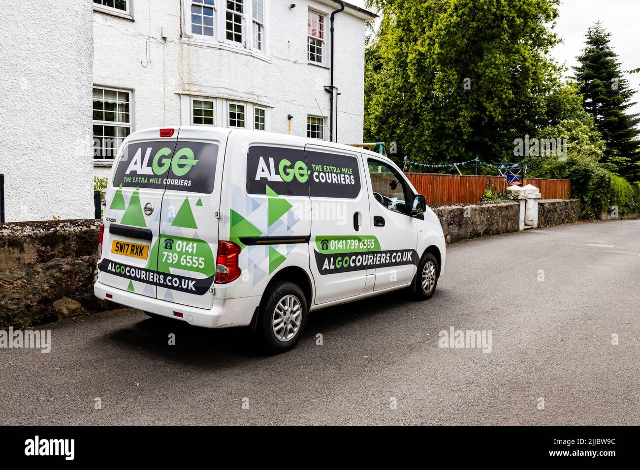 Exterior landscape view of Algo courier van with logos from the extra mile couriers parked outside a residential dwelling, with no people visible Stock Photo