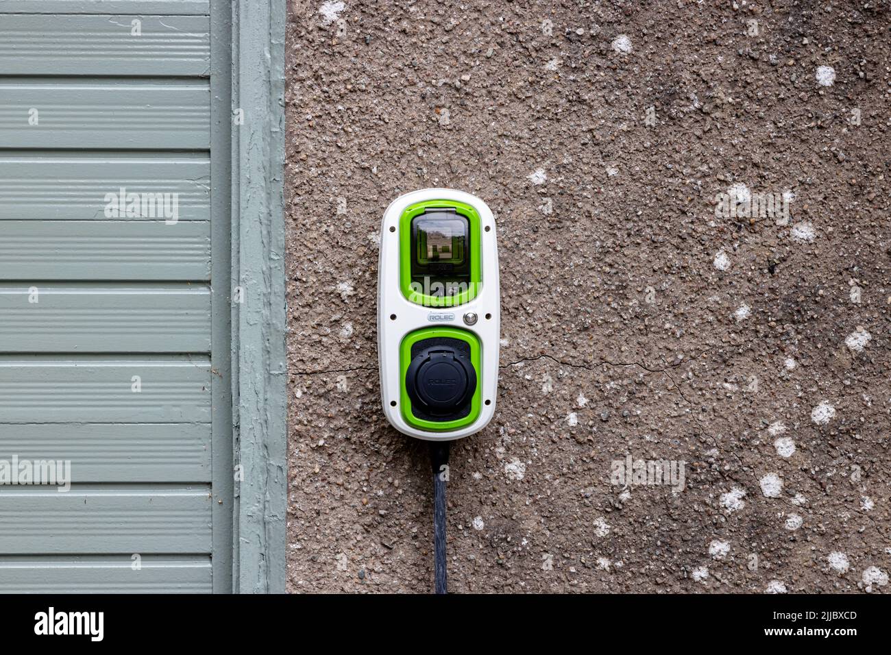 Exterior landscape view of a garage wall mounted Rolec EV Wallpod, an Electric Vehicle or Plug-in Hybrid Charging Point for a residential house Stock Photo