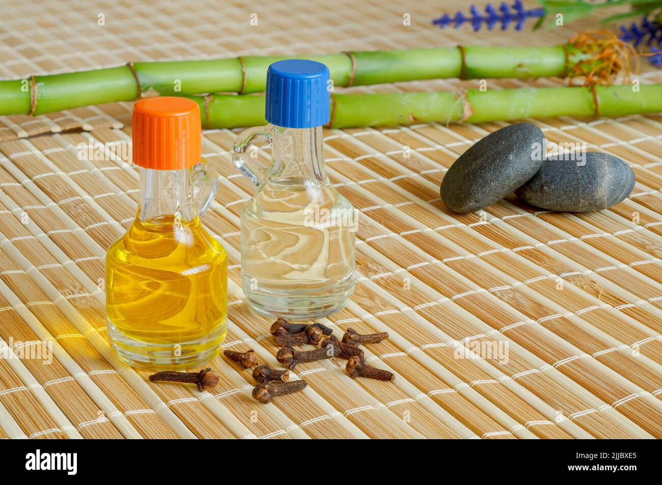 Clove and lavender oil. Bamboo, pebbles, bamboo mat background, essential oils in bottles, zen background concept, spa Stock Photo