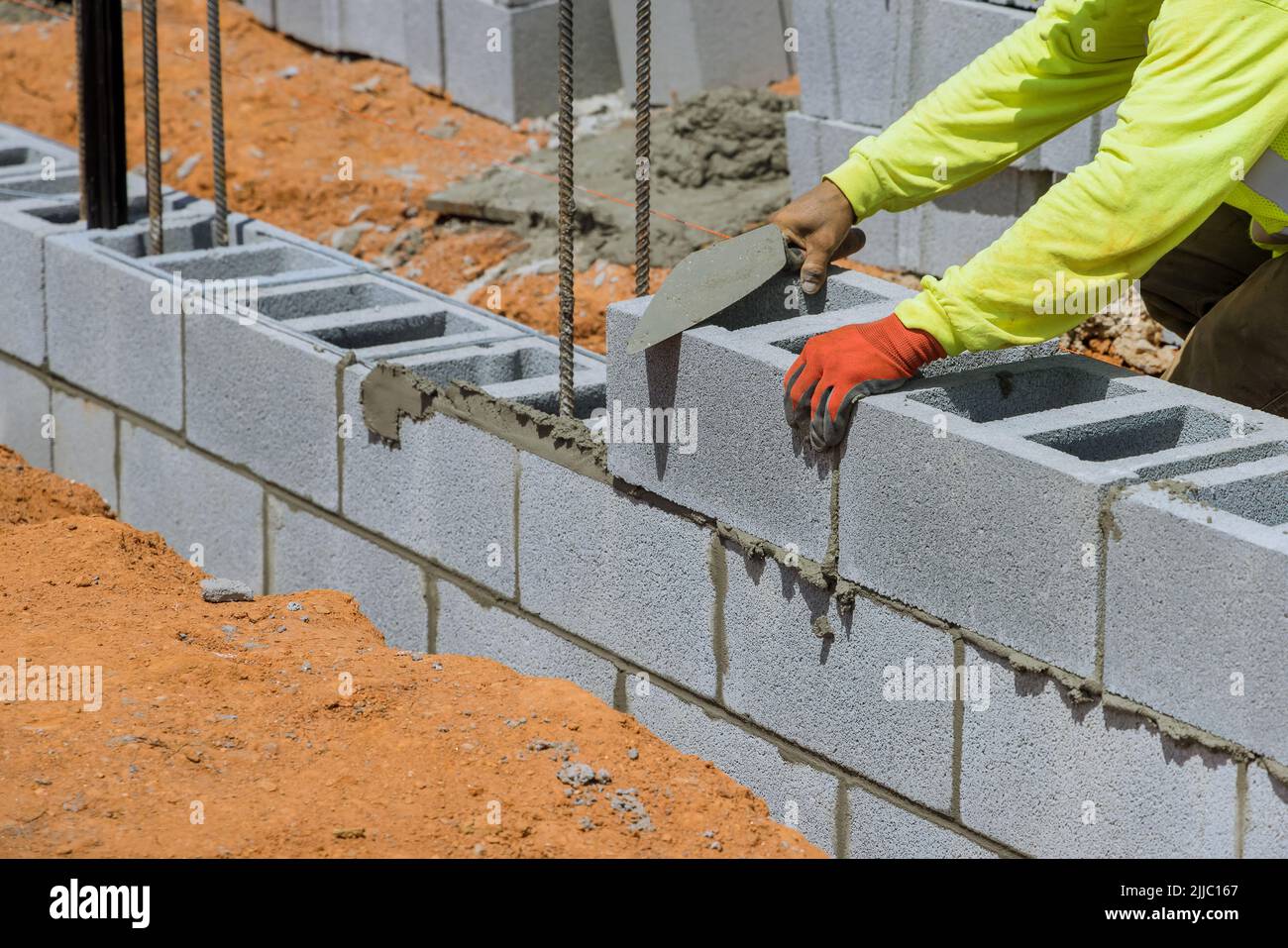 A mason is placing the aerated concrete blocks on the wall as he lays