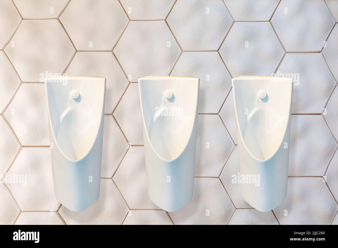 Row of three new design urinals attached to an ecological wall made of recycled natural material Stock Photo