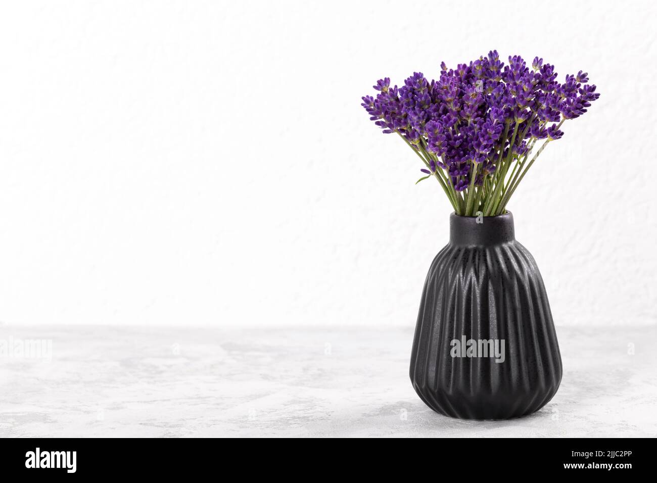 Bouquet of lavender in modern black ceramic vase over grey stone background copy space Stock Photo