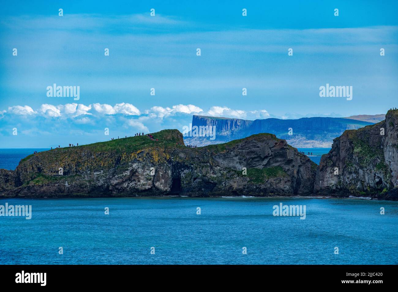 View of Carrick-a-Rede rope bridge from a distance with the dramatic cliffs of Fair Head in the dstance, North Coast, County Antrim, Northern Ireland Stock Photo