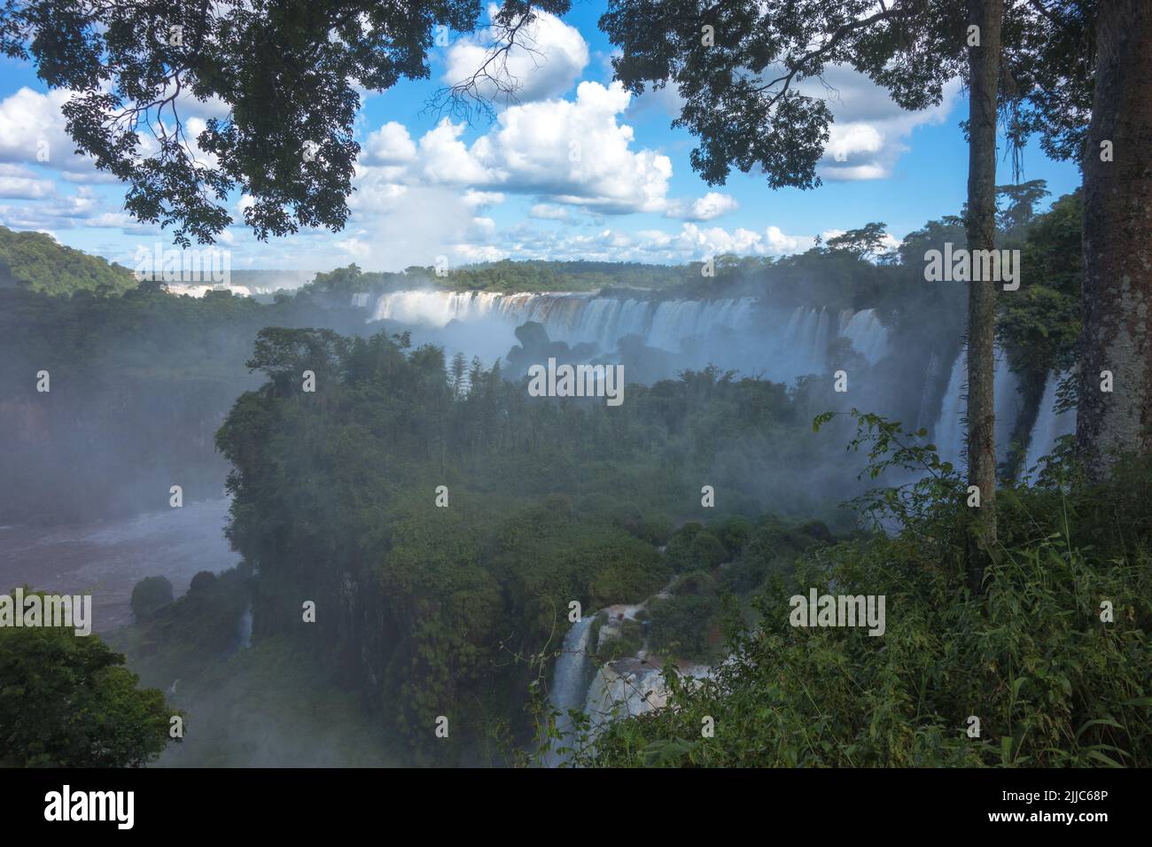Huge beautiful panorama view from Iguazu Fall, Catarata Argentine Side blue sky green forest murky waters of Iguazu river strong current. Stock Photo