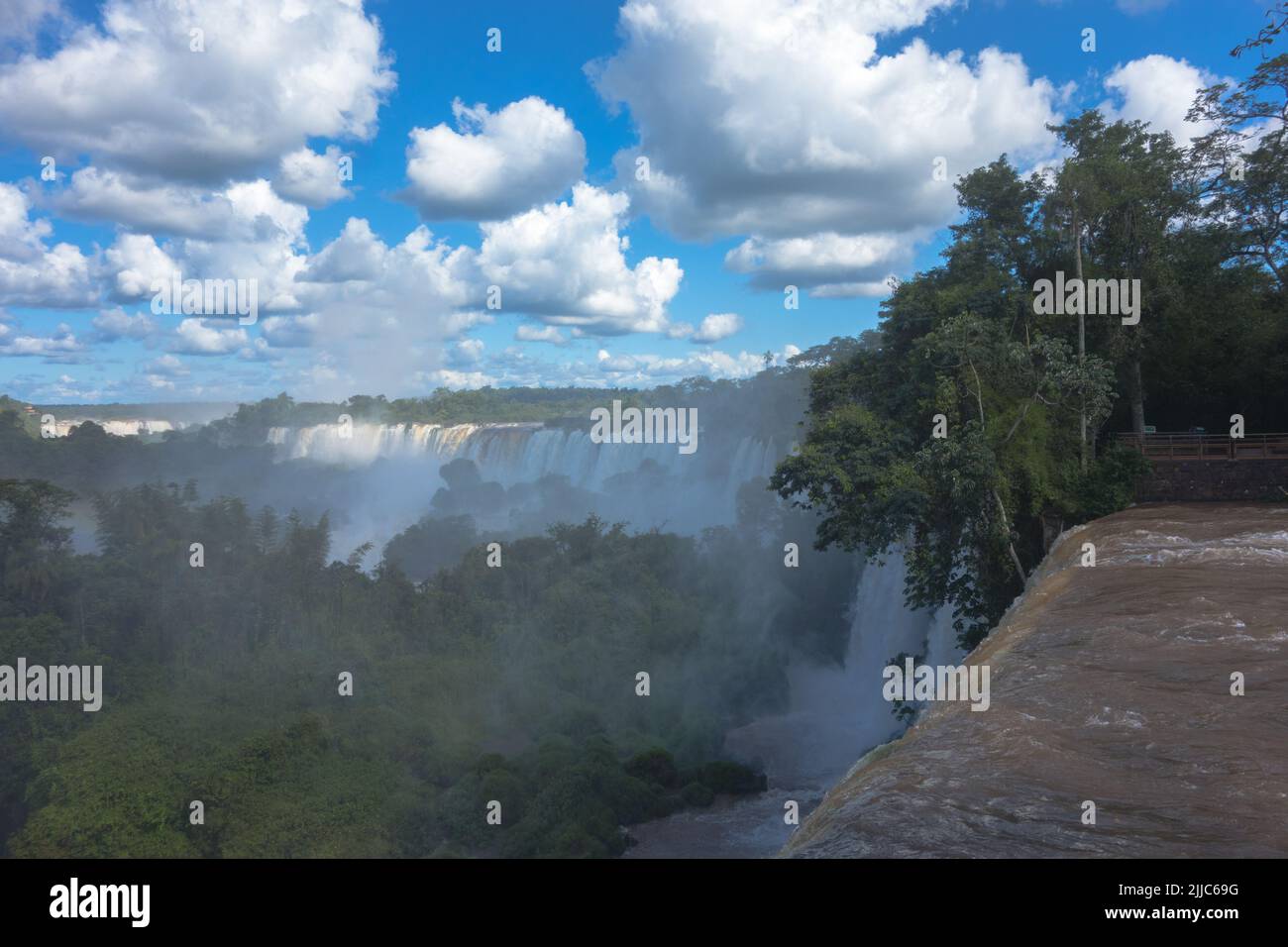 Huge beautiful panorama view from Iguazu Fall, Catarata Argentine Side blue sky green forest murky waters of Iguazu river strong current. Stock Photo