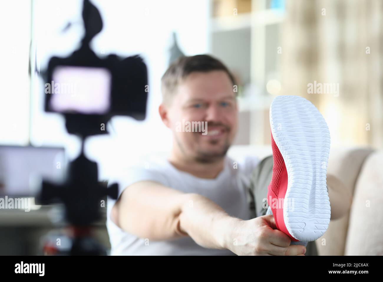Cheerful male blogger calls red sneakers while recording new video for blog Stock Photo