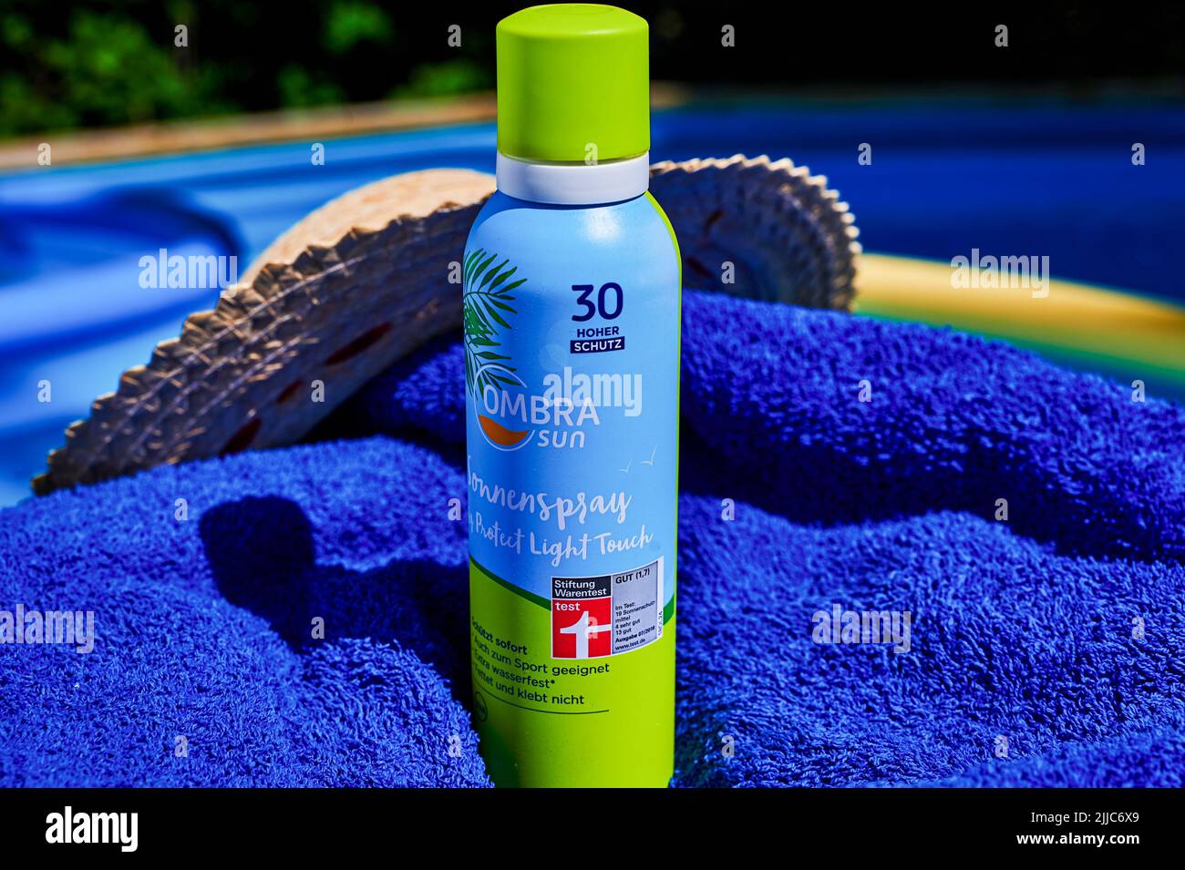 Berlin, Germany - July 24, 2022: Anti-sunburn spray on a blue towel by a swimming pool. Stock Photo