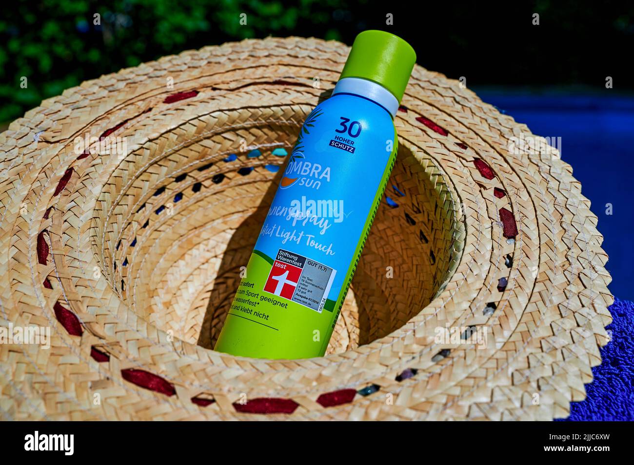 Berlin, Germany - July 24, 2022: Anti-sunburn spray on a blue towel by a swimming pool. Stock Photo