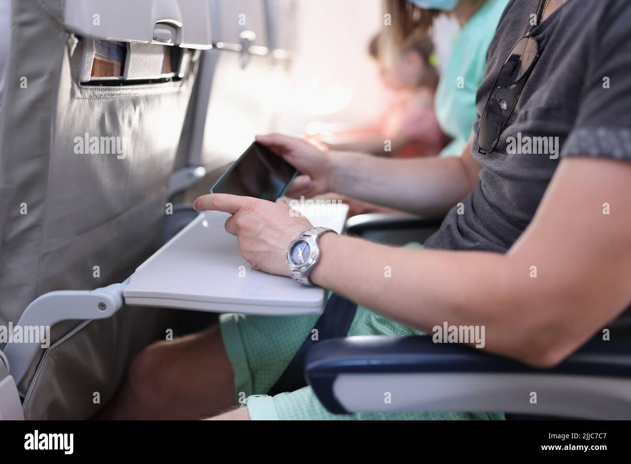 Man hands with a smartphone sits in cabin of airplane or train Stock Photo