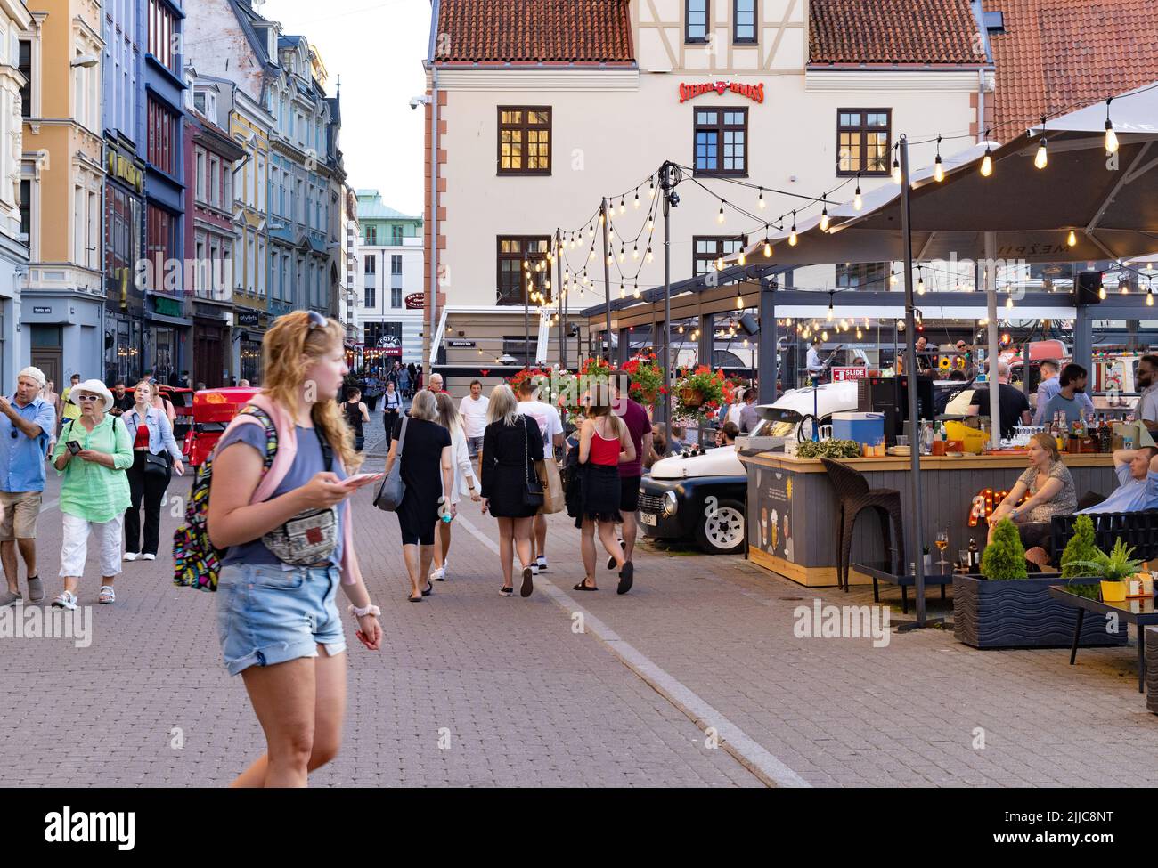 Riga street scene - tourists and crowd of local people mixing on a busy street in the evening as the bars opening, Riga Old Town, Riga Latvia Europe Stock Photo