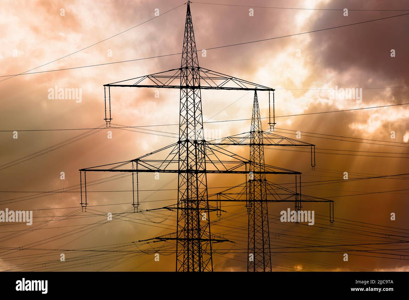 Many elecrtic poles in front of sky with clouds Stock Photo