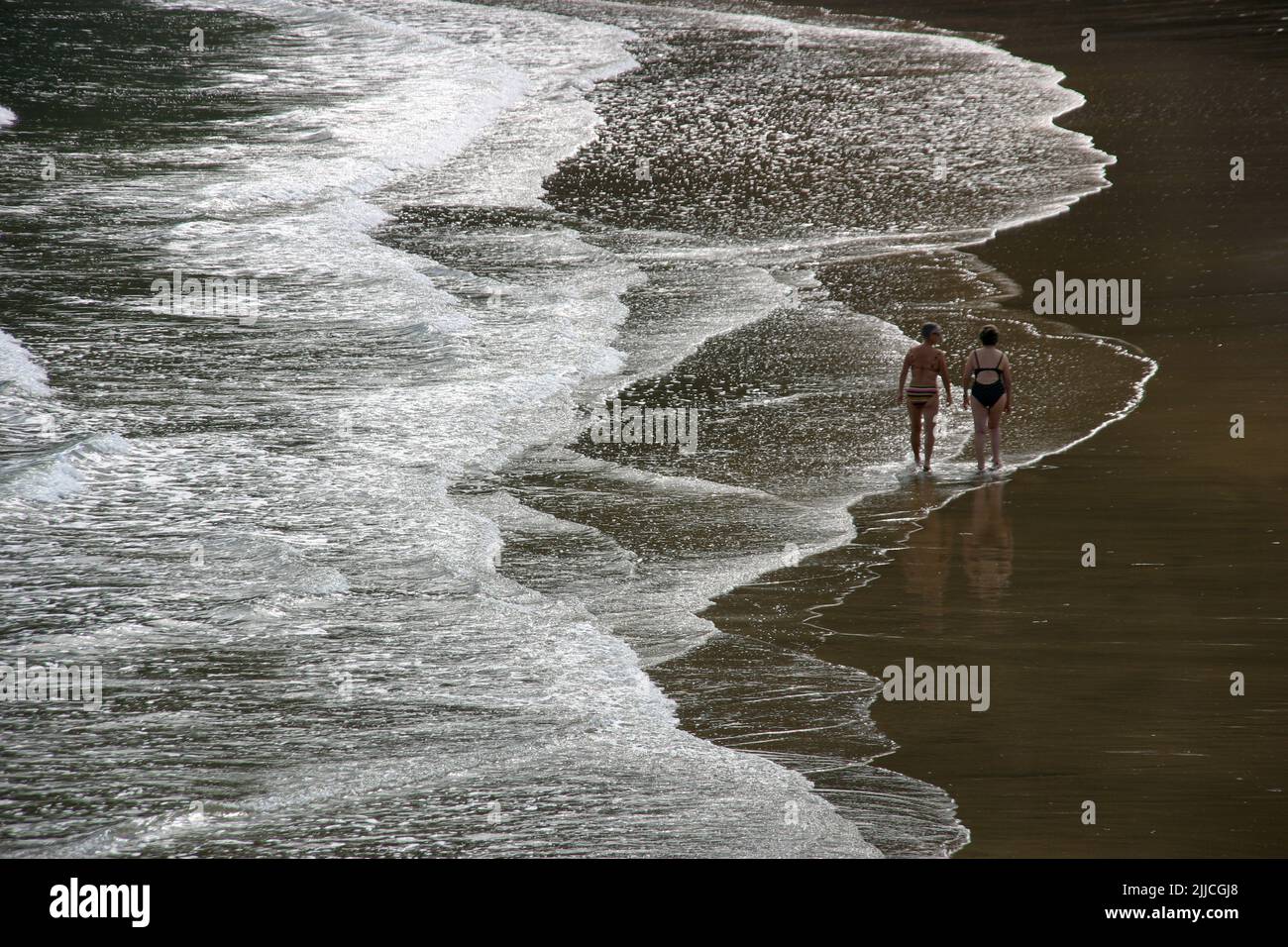 Two persons seen from afar strolling along the surf at Zarautz Beach in Northern Spain Stock Photo