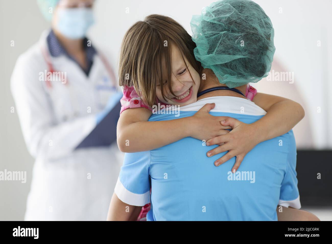 Doctor holds frightened little child girl in arms in clinic Stock Photo