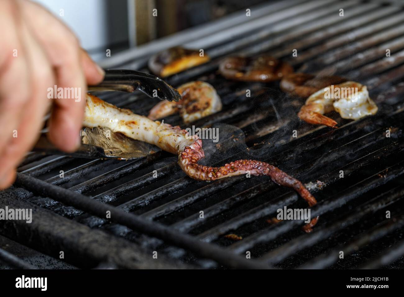 Process of grilling seafood on a barbecue grill over hot coal. Seafood recipes Stock Photo