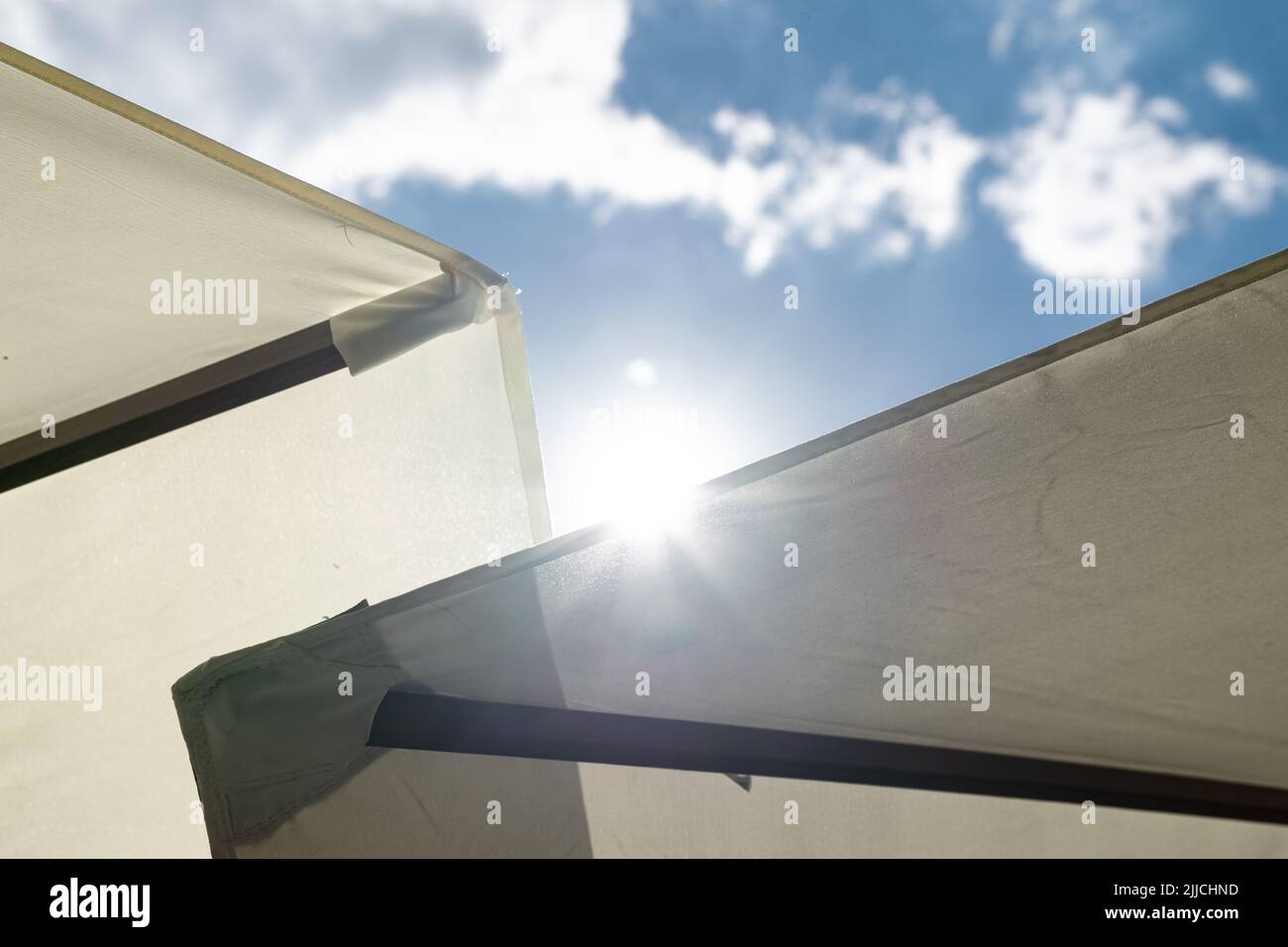 The sun glaring over the rim of a parasol making you feel there is no escape from the heat Stock Photo