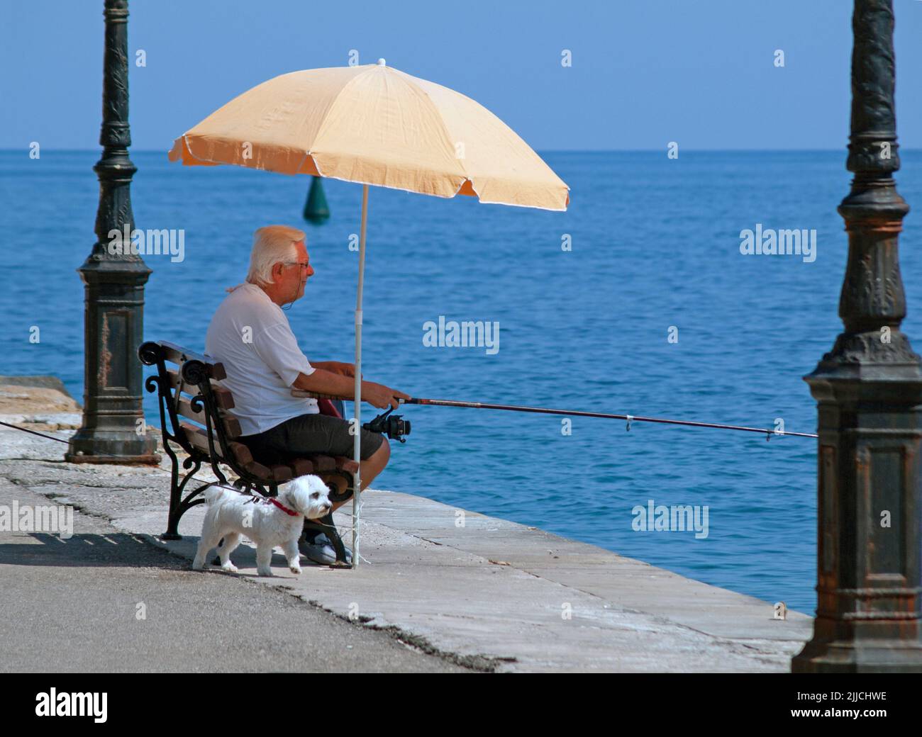 A man fishes in the Old Venetian Harbour of Chania, Crete Stock Photo