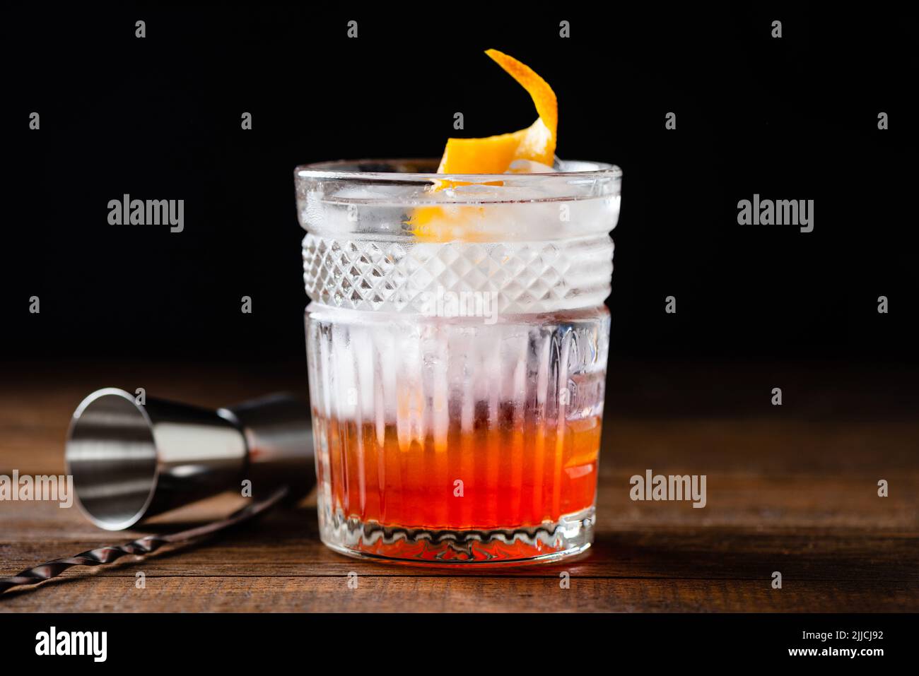 Old fashion alcoholic cocktail with vodka and orange peel on wooden bar