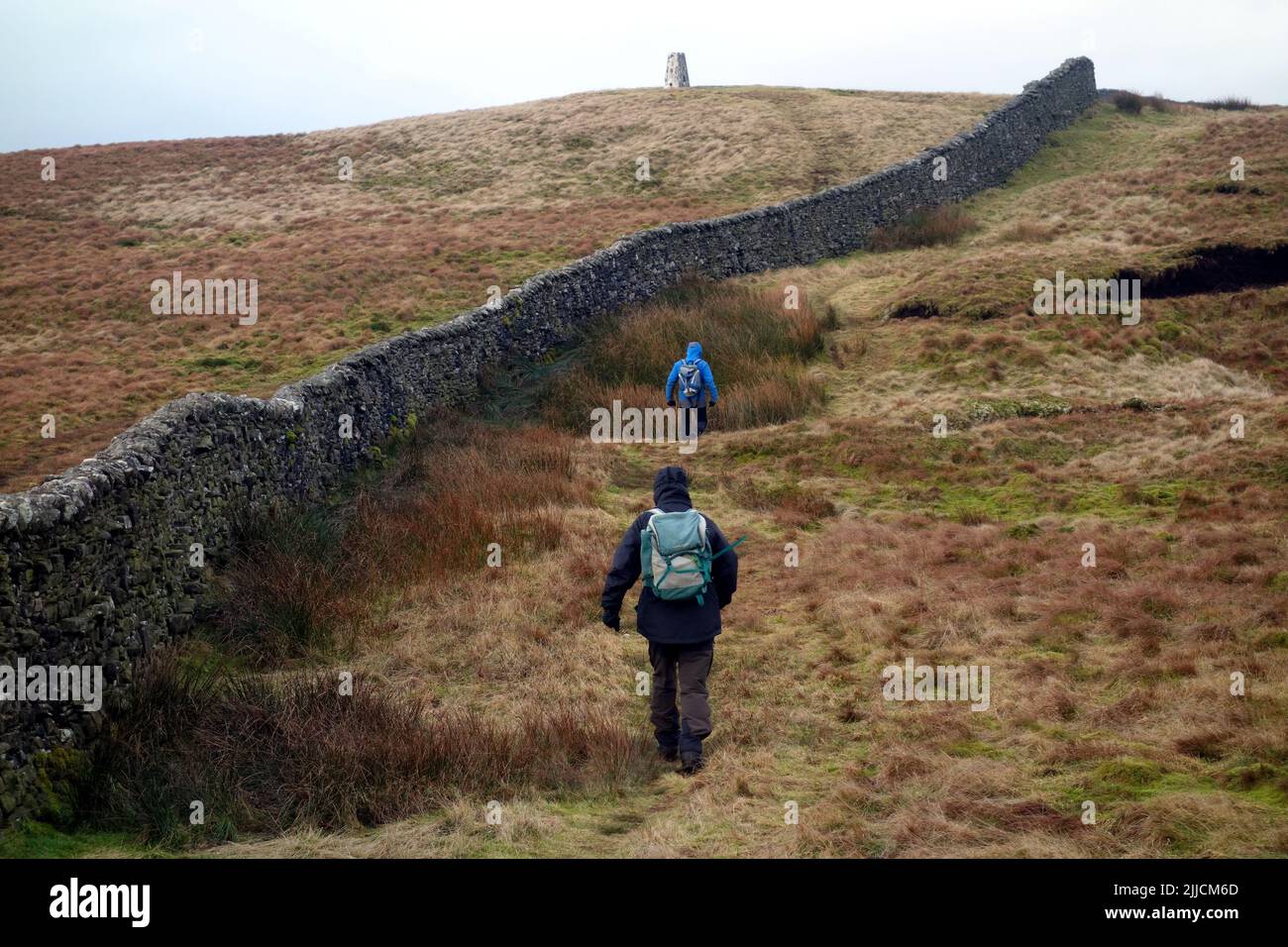 Two Men Walking by a Wall to the Summit Trig Point on 'Horse Head' near Halton Gill in Littondale, Yorkshire Dales National Park, England, UK. Stock Photo