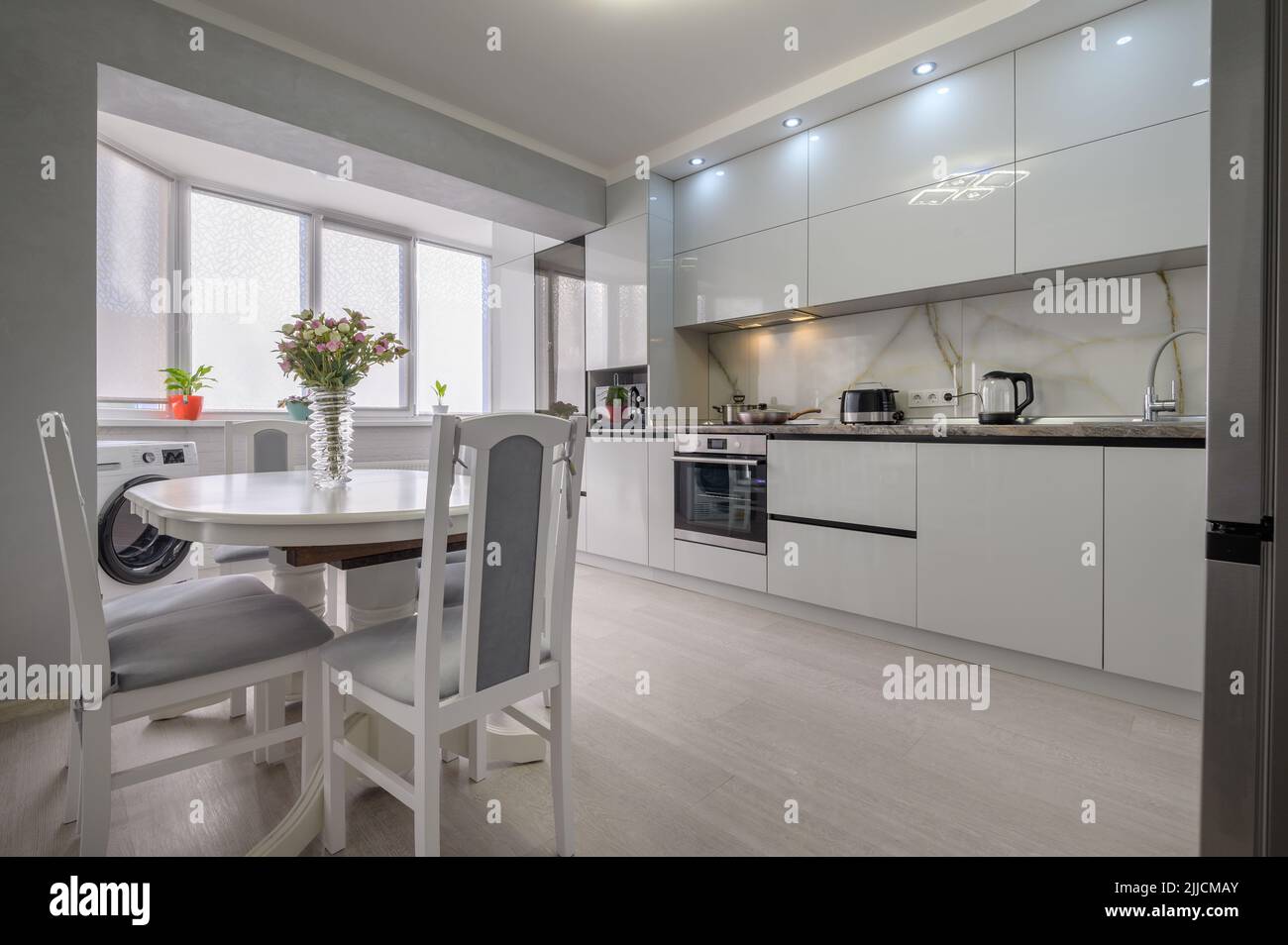 Interior of white modern kitchen with dining table Stock Photo - Alamy
