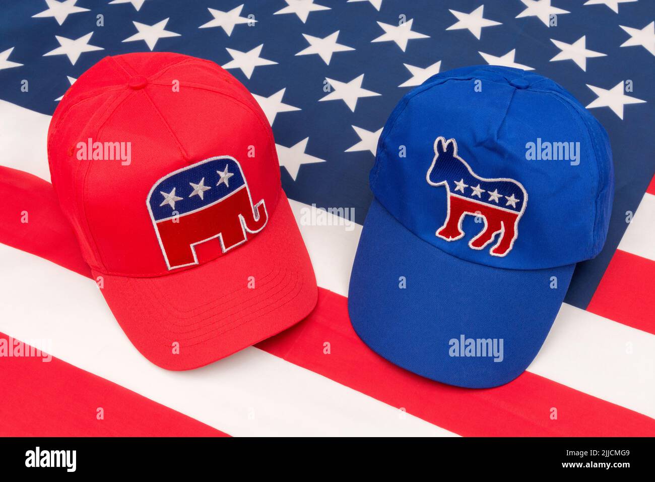 Blue Democrat Party donkey badge hat & MAGA Republican Elephant badge cap on US Stars and Stripes flag. For 2024 US Presidential election in November Stock Photo