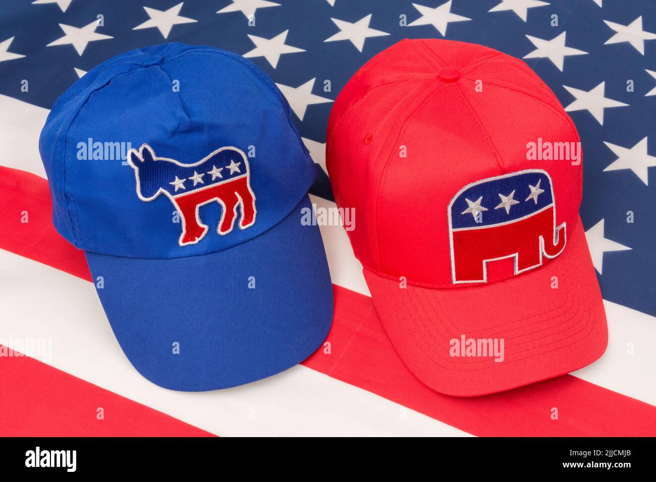 Blue Democrat Party donkey badge hat & MAGA Republican Elephant badge cap on US Stars and Stripes flag. For 2024 US Presidential election in November Stock Photo