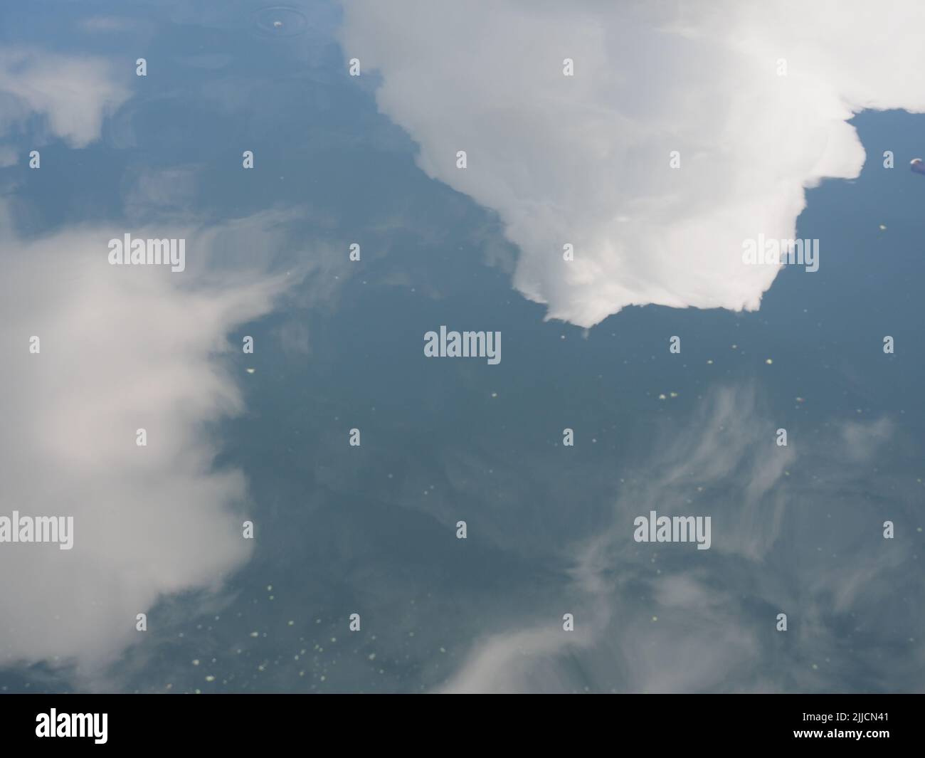 White clouds in a blue sky reflected on the surface of some water Stock ...