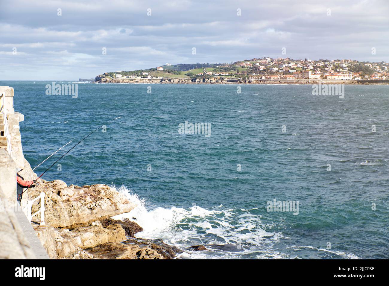 Person angling in a rocky area overlooking a coastal town. Concept travel, vacation Stock Photo