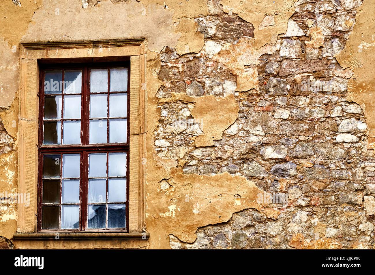 Window with frame from which the paint is peeling off, in a wall of ...