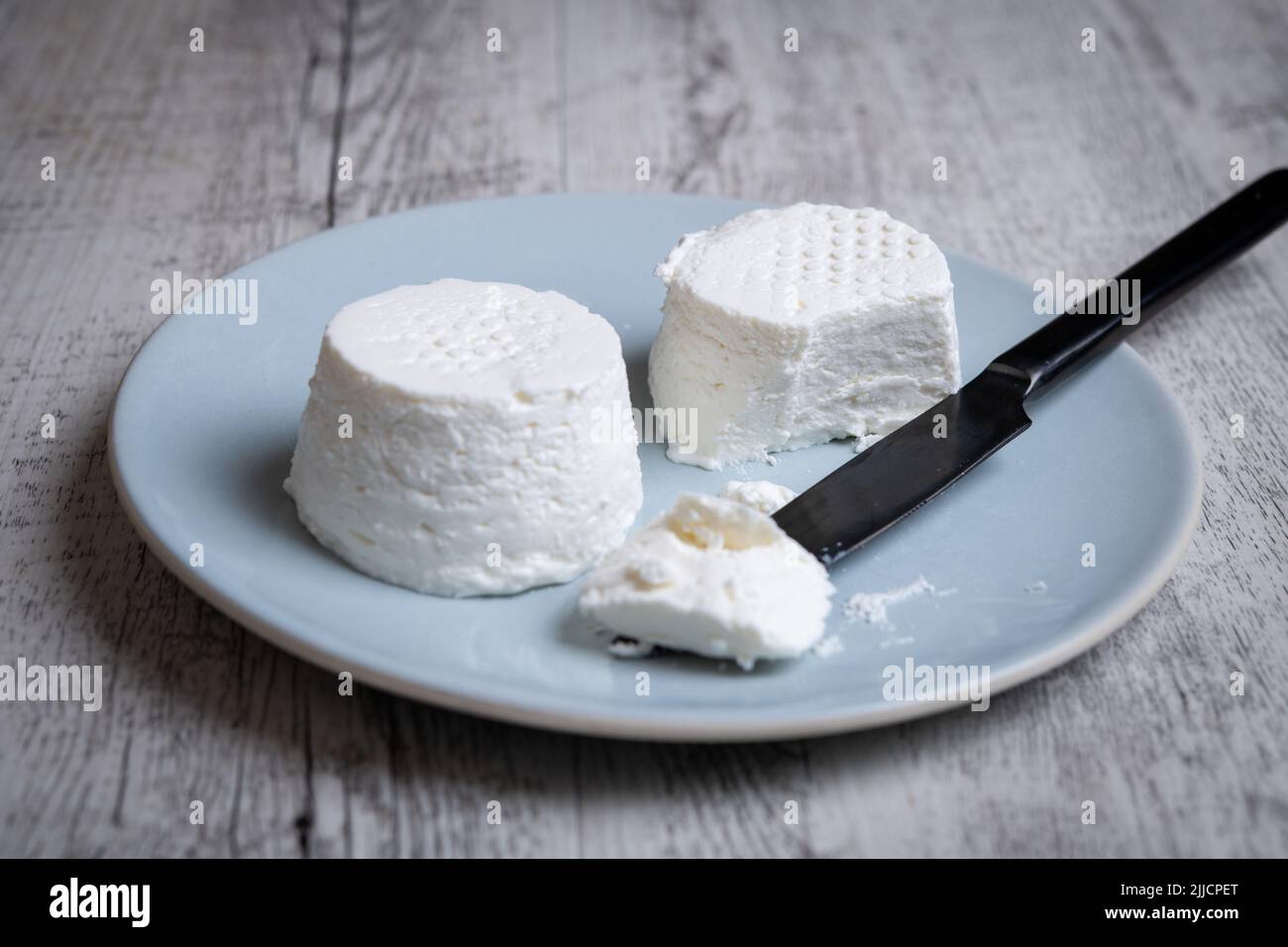 eating a fressh white cheese in a plate on a wooden table Stock Photo
