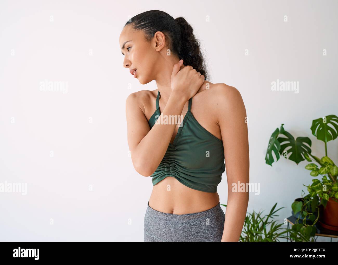 A young multi-ethnic woman holds her neck in pain during yoga Stock Photo