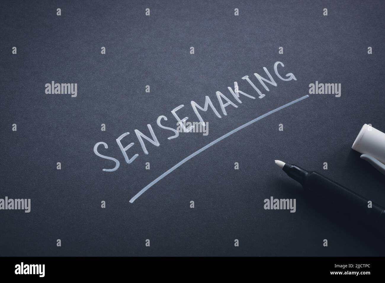 Sensemaking word handwritten on the dark page. Stock Photo