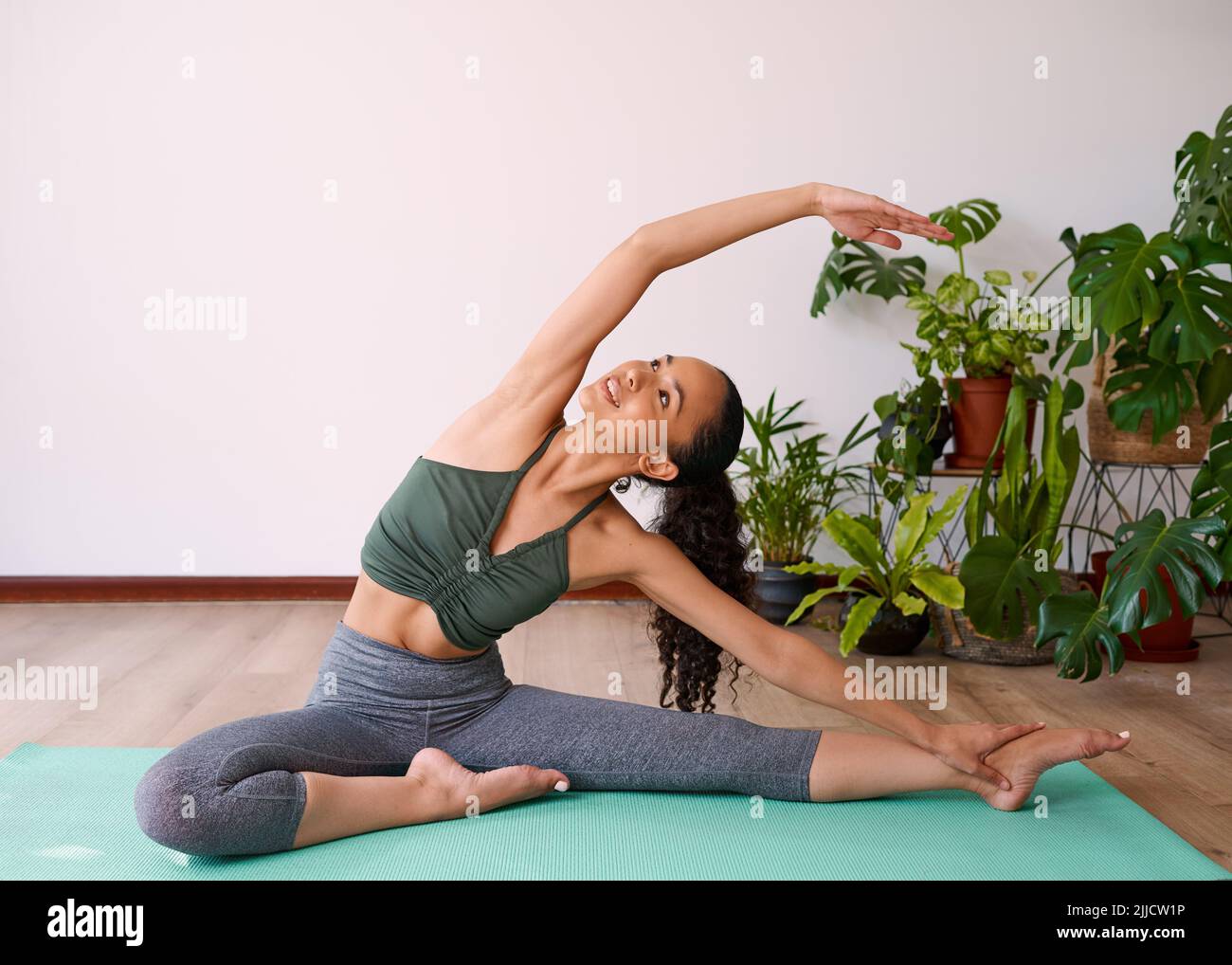 A young multi-ethnic woman reaches overhead in seated side stretch yoga  pose Stock Photo - Alamy