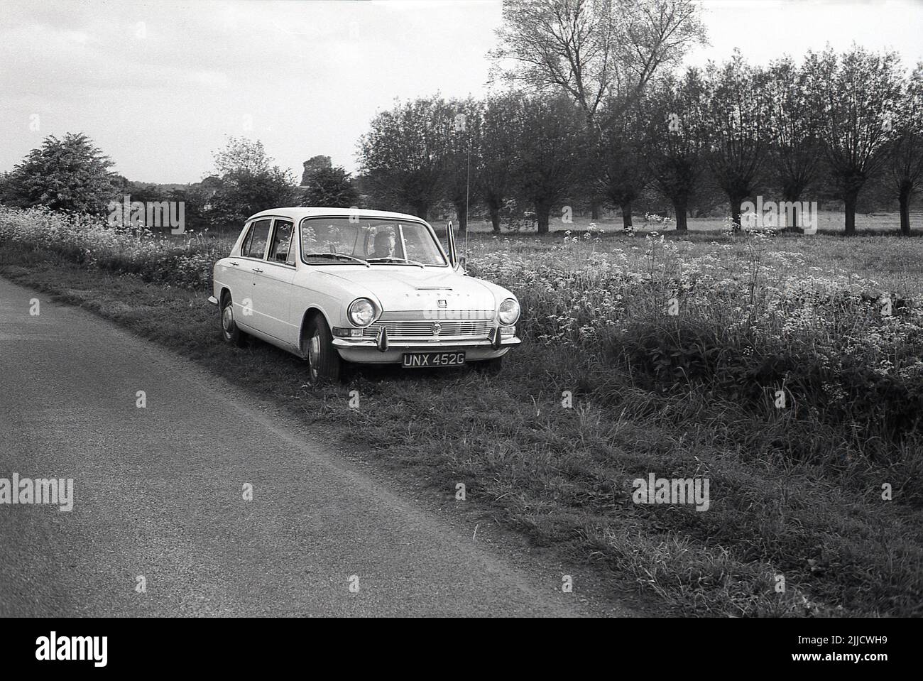 1970s, historical, a gentleman sitting in the passenger seat ot a Triumph Dolomite car of the era, parked on a grassy verge beside a rural road, England, UK. A small saloon car, the Triumph Dolomite was made by the Tiumph Motor Company which was a part of the hugh British Leyland Corporation (BL. The car was produced in Canley, Coventry, between 1972 and 1980. Stock Photo