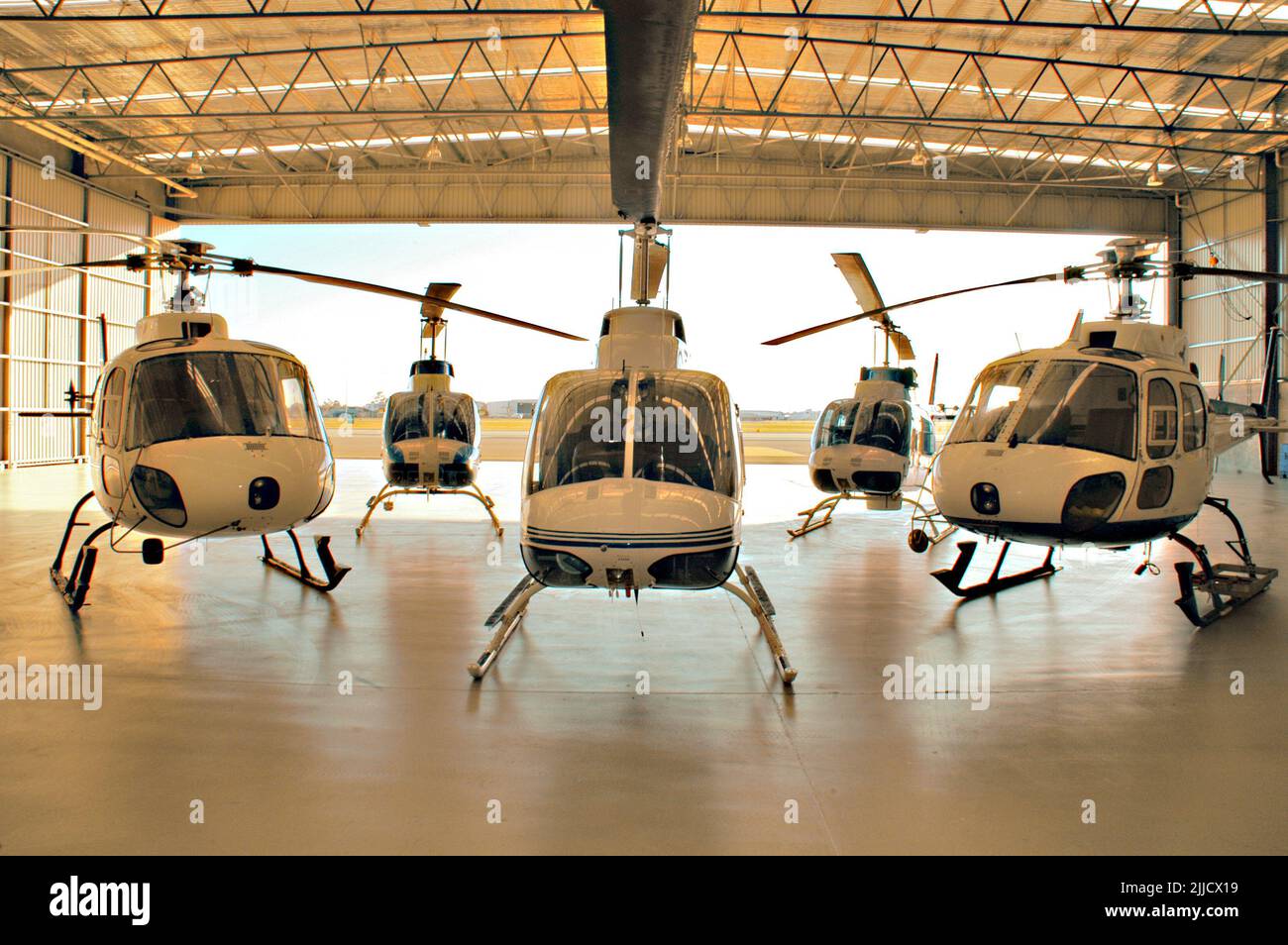 Eurocopter AS350 Squirrel helicopters and Bell Jet Ranger helicopters inside a hangar. Stock Photo