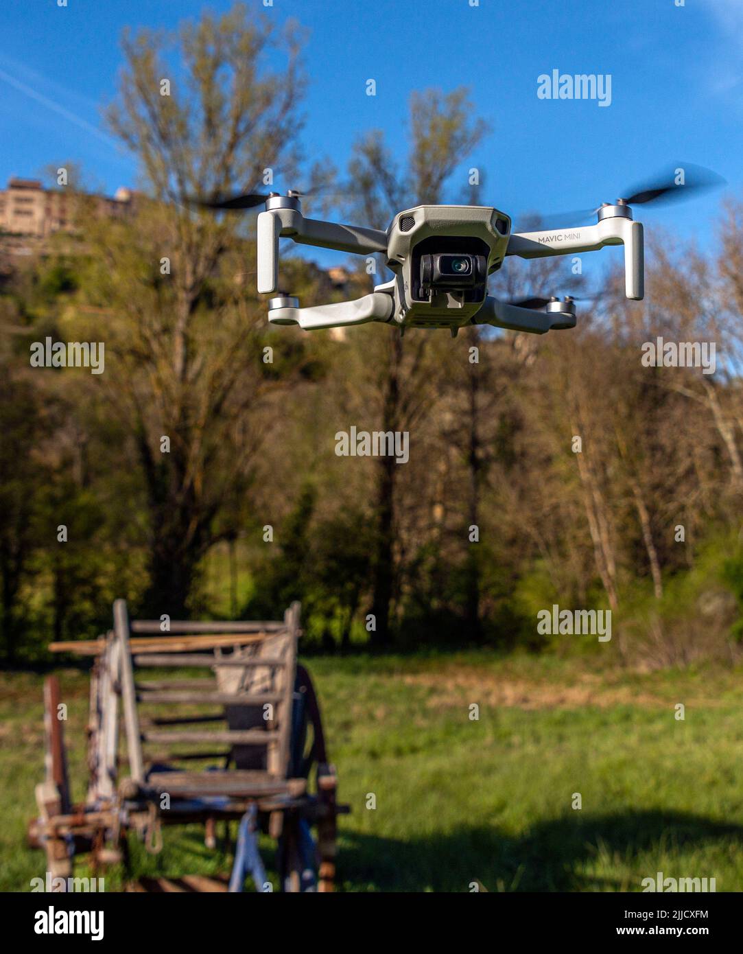 A portrait format view of a DJI Mavic Mini drone hovering above the ground. Stock Photo