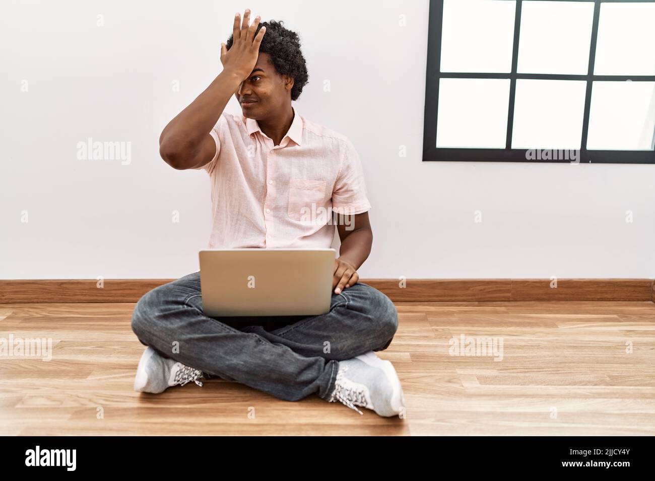Remember Sitting African man with curly hair using laptop sitting on the floor surprised ...