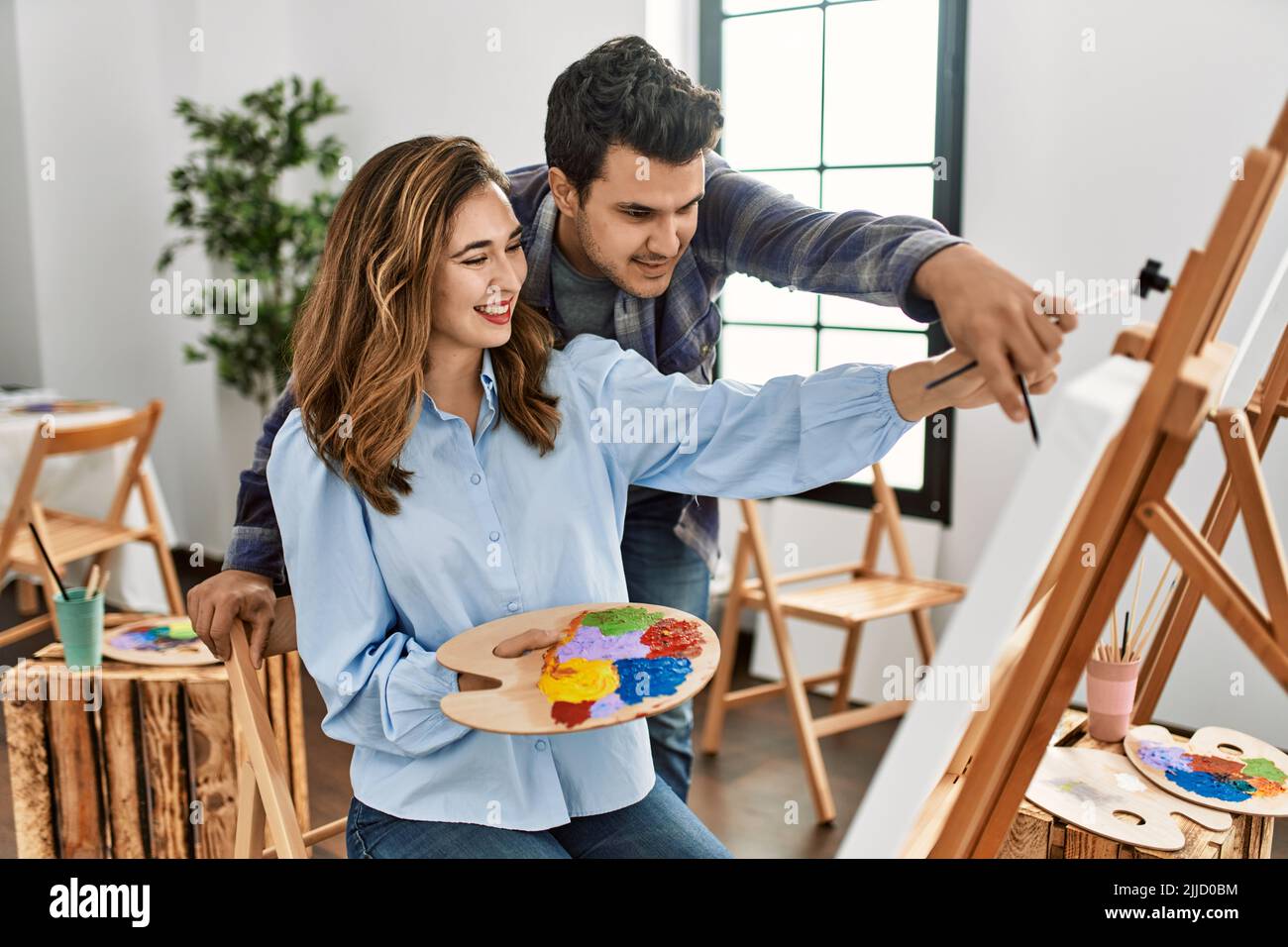 Student and teacher smiling happy painting at art school Stock Photo ...