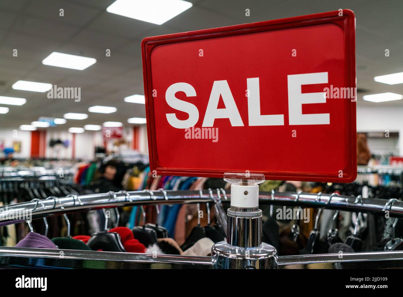 Red sale sign on rail of clothes in a high street shop or store Stock Photo