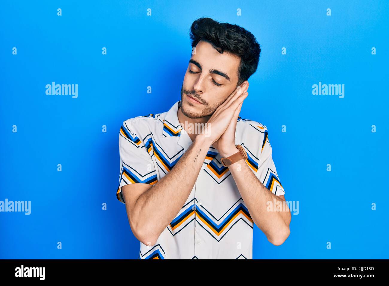 Young hispanic man wearing casual clothes sleeping tired dreaming and ...