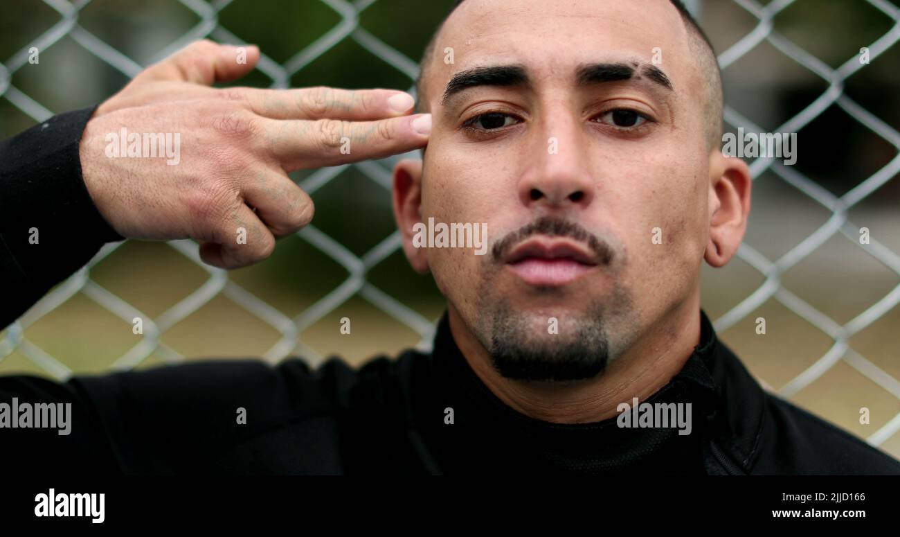 Hispanic man pulling trigger. pointing at head with pretend gun, headshot with finger Stock Photo
