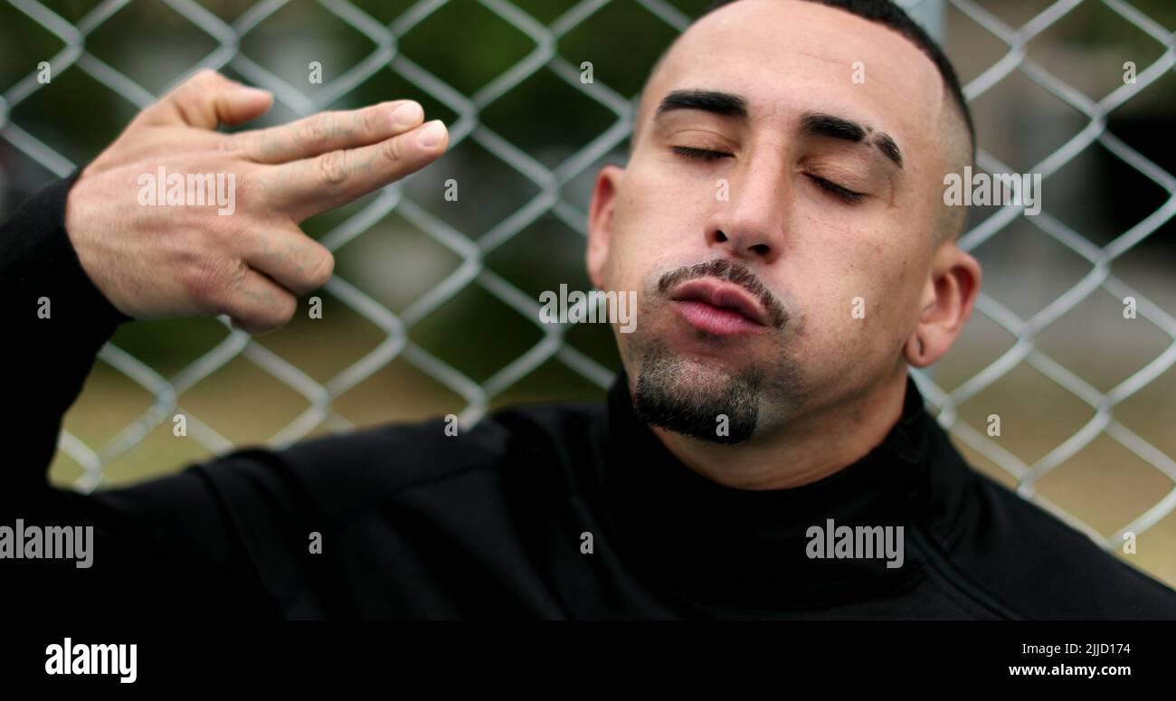 Hispanic man pretending to shoot own head shot with hand Stock Photo