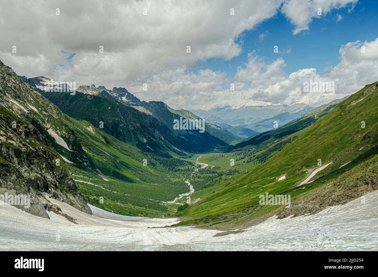 snowy mountain valley with blue sky and clouds Stock Photo