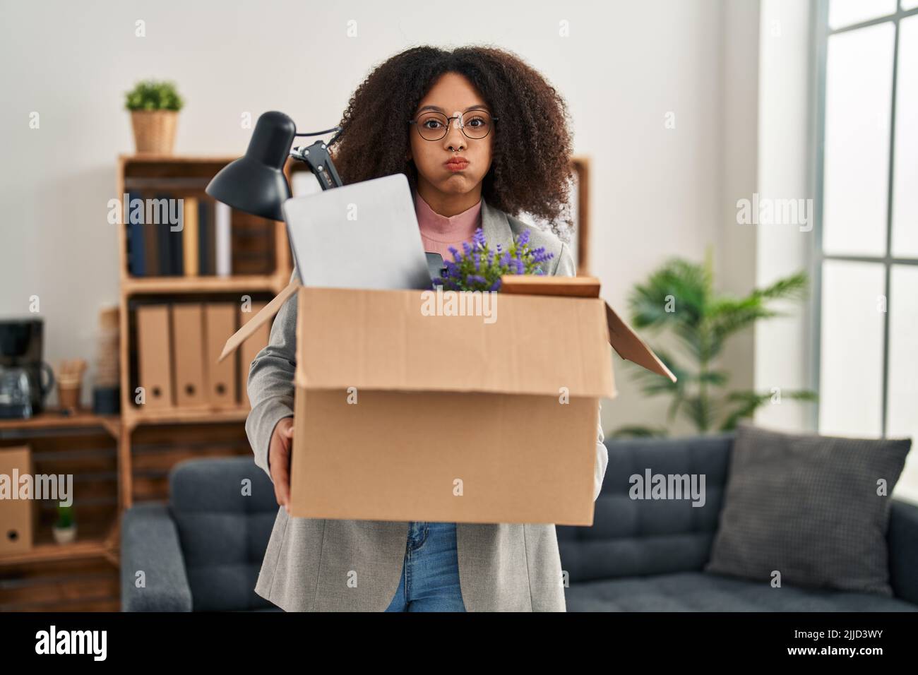 Young african american woman moving to a new office holding box with ...